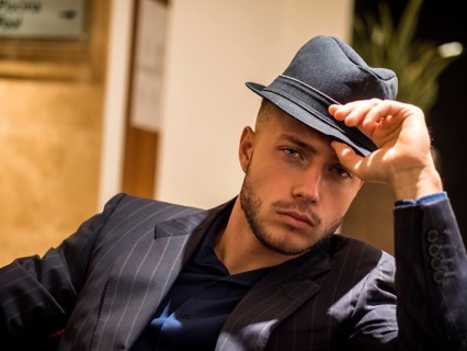 Handsome elegant man in hotel or night club lounge, wearing business suit and fedora hat, looking