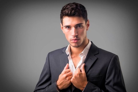 Young businessman confidently posing in front of camera, wearing business suit without neck-tie,