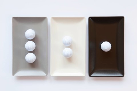 Different ceramic dishes with golf balls on over white background, rectangle dish