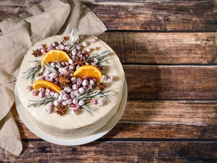 Winter homemade cake on wooden background. White cream christmas cake decored rosemary,