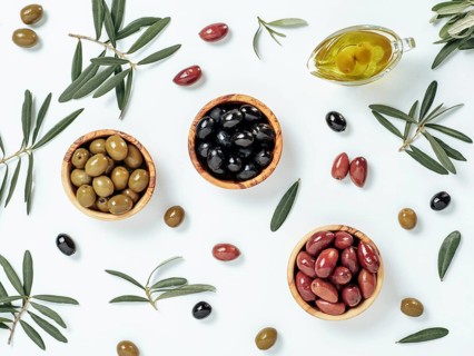 Set of green olives, black olives and red kalmata olives and extra virgin olive oil on white