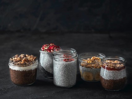Set of chia pudding in different glass jars on dark table. Assortment of chia puding with different