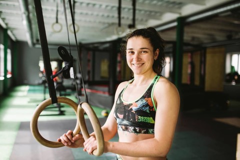 Beautiful girl doing an exercise on the gym rings in the gym. Happy and smiling