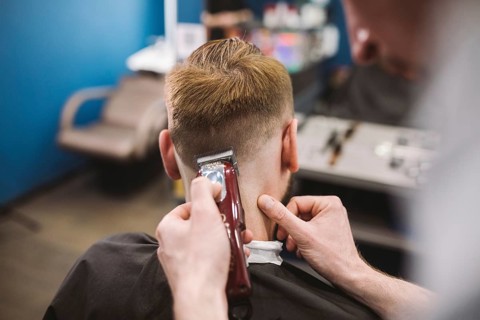 Close up shot of a man getting a trendy haircut at a hair salon. Male caucasian hairdresser serving