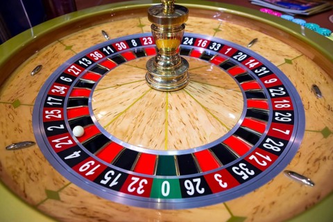 Roulette table in casino. Ball in the rotating gambling machine. Wooden roulette wheel