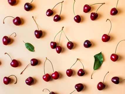 Fresh cherries scattered on yellow background. Creative fresh cherry pattern background with copy