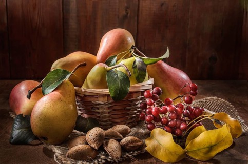 Ripe pear and a bunch of viburnum berries on a dark wooden background in a rustic style