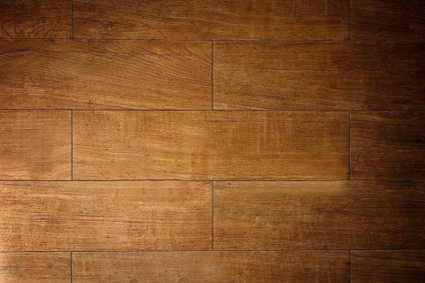 Warm light illuminating textured brown wooden floor tiles, creating a rustic and inviting ambiance