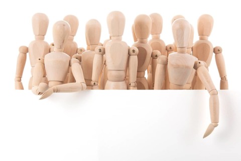 Many wooden mannequins behind board isolated over white