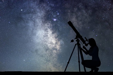 Girl looking at the stars with telescope. Milky Way galaxy
