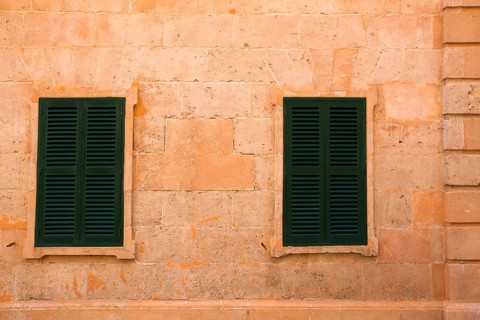 Ciutadella Menorca wooden shutter window on grunge yellow downtown wall at Balearic islands