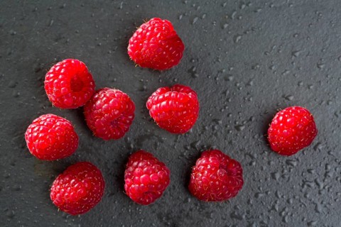 Berries raspberry on black background macro closeup with fresh water drops