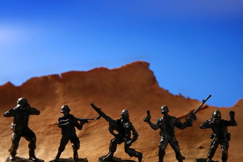 War metaphor, toy little soldiers fighting on wooden mountain