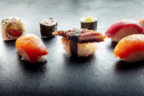 Sushi on a black slate plate. Nigiri with eel, salmon and tuna, roll with avocado and maki with