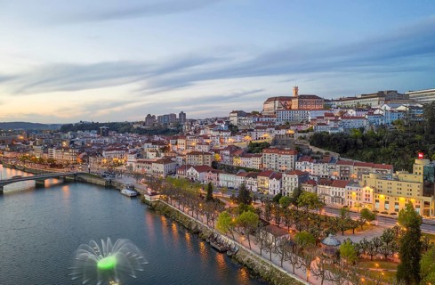 Coimbra drone aerial city view at sunset with colorful fountain in Mondego river and beautiful