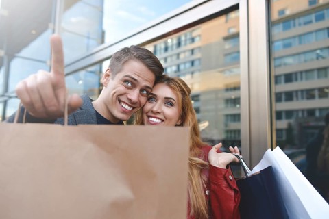 Beautiful couple with shopping bags is talking and smiling while doing shopping in the mall focus