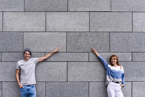 Cheerful couple at the street, show a big sale, or nice offer. Advertise concept. People, travel