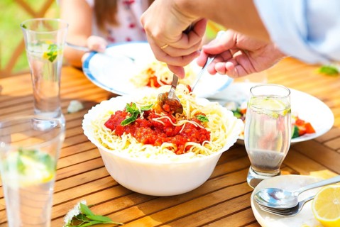 Family dinner variety of Italian dishes on wooden table in the garden