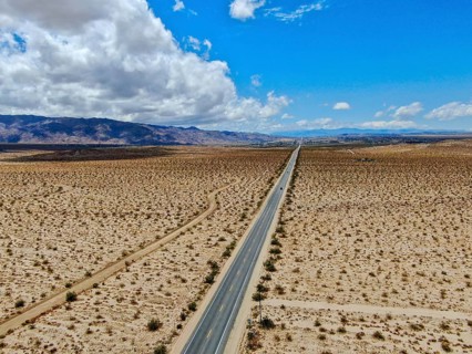 Aerial view of endless desert straight dusty asphalt road in Joshua Tree Park. USA. Long straight