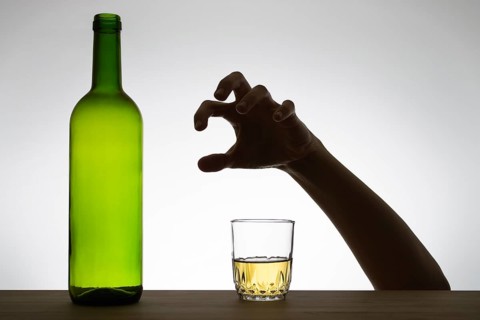 Silhouette of a hand reaching for a glass of wine