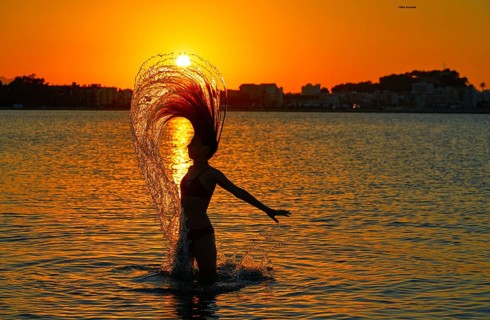 Girl flipping hair flip at sunset beach in orange sky