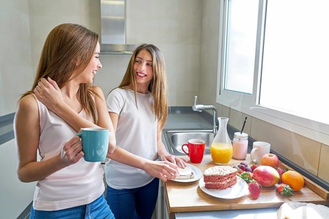 Best friends girls teens breakfast in kitchen having fun
