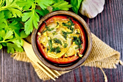 Fish baked in tomato in Zandvoort in clay bowl on a napkin of burlap, parsley on a dark wooden