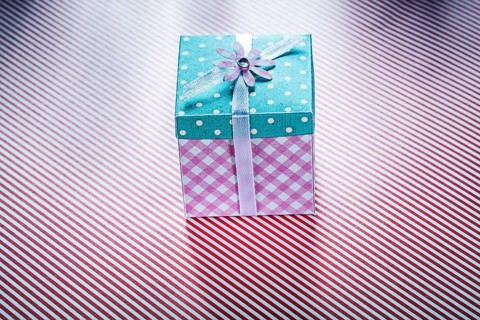 Gift box on striped fabric background top view celebrations concept