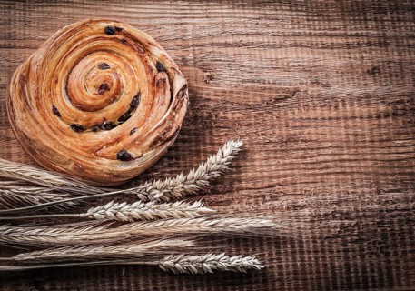 Rich raisin bakery bunch of wheat ears on oak wooden board food and drink concept