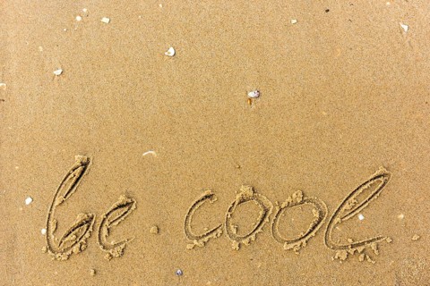 Be cool written on the beach. sand background