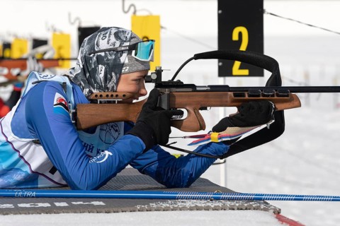 Sportswoman biathlete aiming, rifle shooting in prone position. Biathlete Arina Soldatova Kamchatka
