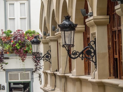Historic lanterns hanging on the wall of a building with arches and plants in the city, la palma,