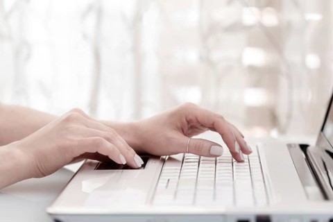Close up of female hands using modern computer, high key. Blogger concept