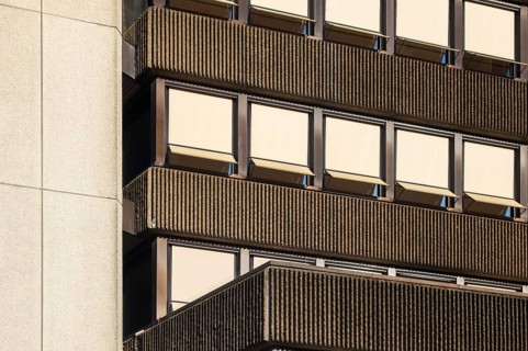 Sunlight illuminating a modernist building facade with ribbed concrete and rows of windows with
