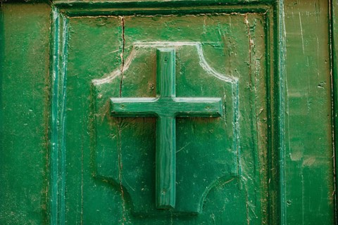 The entrance to the church. Cross on a wooden door green