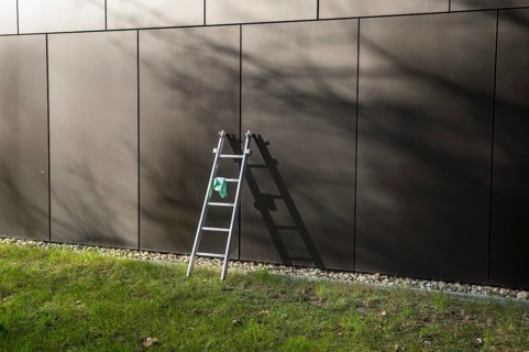 Cleaning crew equipment left on grass lawn in front of modern architecture building facade during