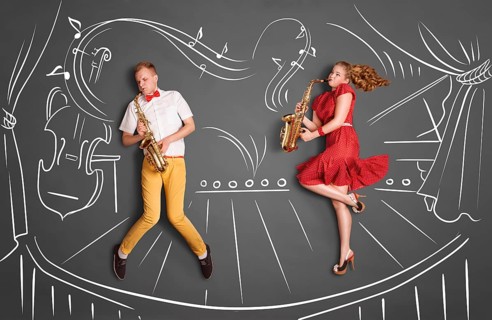 Love story concept of a romantic couple against chalk drawings background. Musician couple playing