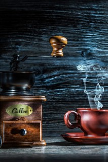Steamy coffee cup and mill on vintage wood