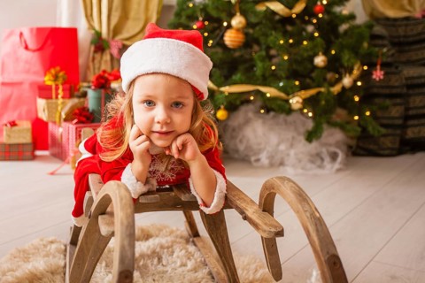 Little child in christmas hat dreaming about christmas miracle. Girl makes a wish an new year night