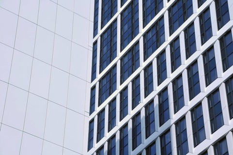 Close up detail of tall high rose modern apartment buildings with white cladding and dark windows