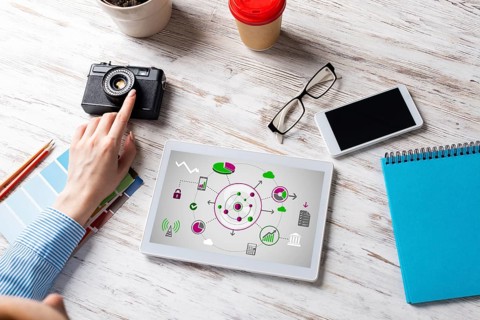 Blogger sitting at desk with tablet computer and camera. Mobile smart devices in business processes