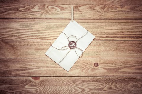 Envelope hanging on rope on wooden background