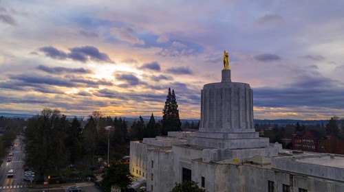 The state capital building adorned with the Oregon Pioneer with downtown Salem in the background