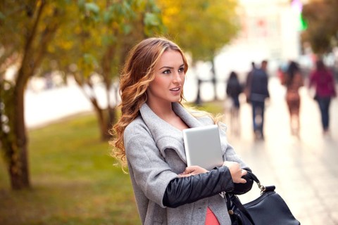 A businesswoman with a tablet walking in a city park