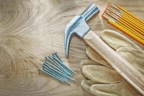Set of protective gloves wooden meter claw hammer nails on wood board construction concept