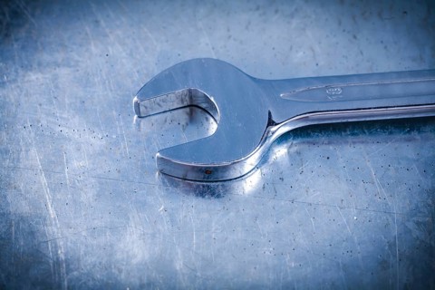 Stainless spanner wrench on scratched metallic background top view construction concept