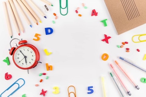 Creative flat lay back to school concept with alarm clock, color school and office supplies on