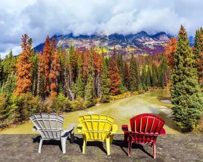 Scenic autumn in the Rockies of Canada. Three deck chairs stand over the forest and river.