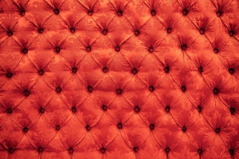 Close up background texture of scarlet red capitone genuine leather, retro Chesterfield style soft