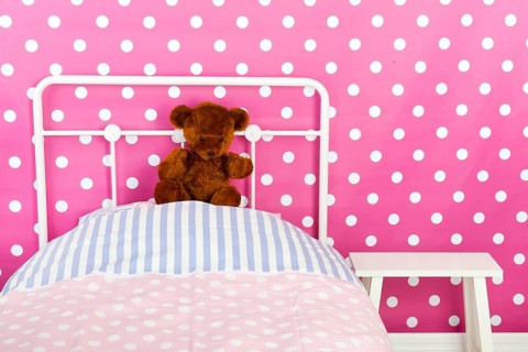 Girls bedroom with pink wall paper and stuffed bear